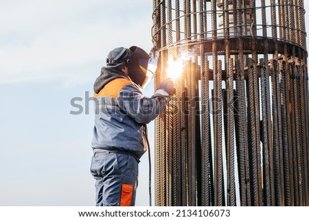 Workers is welding metal parts of concrete bridge
