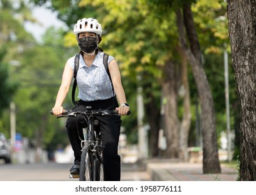 Workers Women Go Cycling In The City To Work.She Wears A Mask