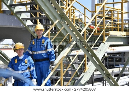 Workers in work clothes in a rafinery - modern equipment and buildings of the factory for production of fuel and gas from petroleum - closeup photo