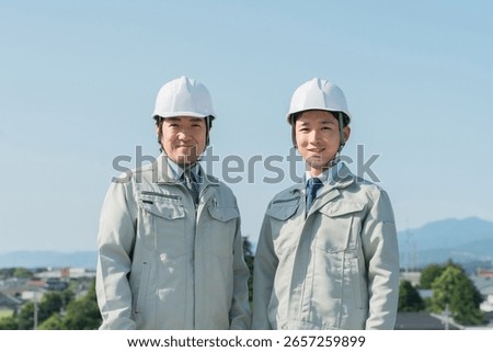 Workers in work clothes standing in the blue sky (construction, architecture, design, real estate, civil engineering, construction, site supervision, transportation)
