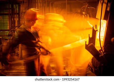 Workers work at a metallurgical plant. Liquid metal is poured into molds. Worker supervising metal melting in furnaces. - Powered by Shutterstock