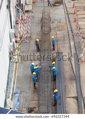 workers work together to make stake of building by steel wire