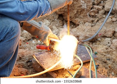 Workers are working connect copper grounding or ground wire protection system. Welding copper ground wire at construction site.