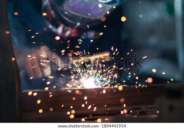 Worker,welding in a car factory with sparks,\
manufacturing,\
industry