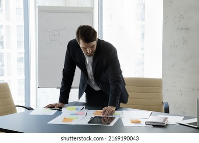 Workflow, modern tech, apps concept. Millennial businessman in suit working in modern boardroom do paperwork, makes sales statistics analysis, prepare report or on-line presentation looks concentrated - Shutterstock ID 2169190043