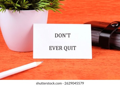 Workforce Reduction, Downsizing, Reorganization, Restructuring concept. Text DO NOT EVER QUIT written on a card next to a small potted plant and stationery.