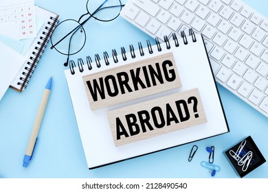 working abroad. text on wooden blocks on a blue background. business concept - Shutterstock ID 2128490540