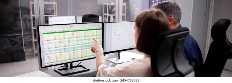 Working Analyst on Desktop PC with Spreadsheets in Background