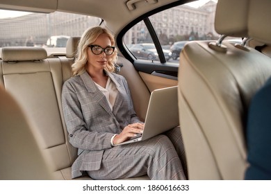 Working Anywhere. Attractive focused businesswoman in stylish classic wear working on laptop while sitting in the car. Business concept. Work concept. Success