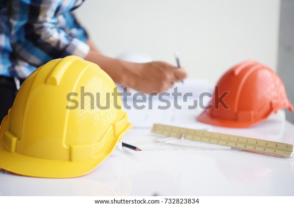 Working of architect sketching\
a construction project at site construction work on his plane\
project.