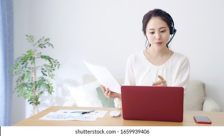 Working asian woman in the living room. Telemeeting. Video conference. Remote work.