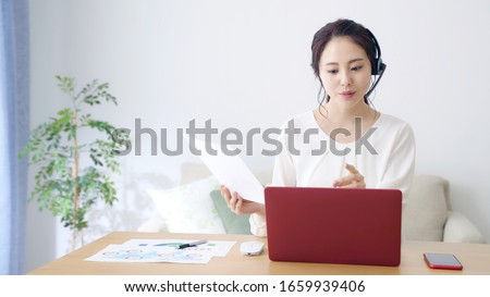 Working asian woman in the living room. Telemeeting. Video conference. Remote work.