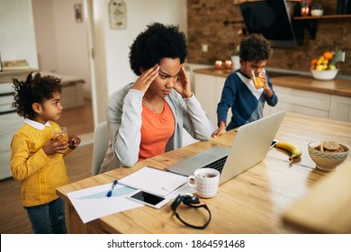 Working Black Mother Using Computer And Trying To Focus On Work While Her Kids Are Around Her At Home. 