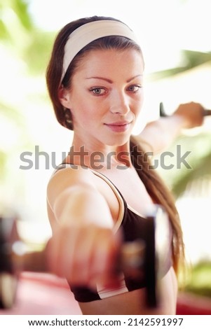 Working for the body I want. Shot of an attractive young woman working out with dumbells.