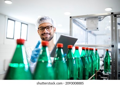 Working In Bottling Water Factory And Production Line Worker Checking Quality Of Beverage And Plastic Packaging.