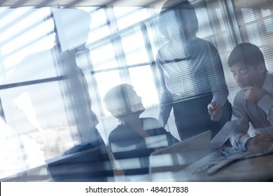 Working businesspeople behind glassy walls