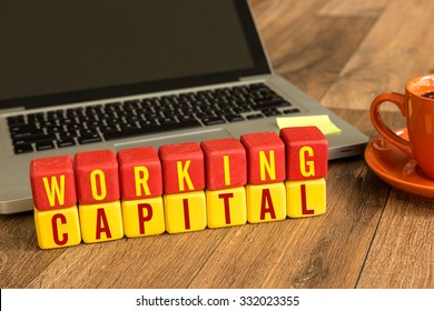 Working Capital written on a wooden cube in front of a laptop