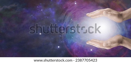 Working with Cosmic healing orb energy - male holding an energy ball between his open parallel hands against a vast expanse of deep space with copy space for spiritual message
