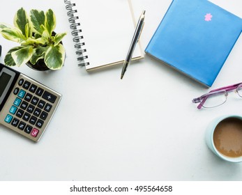 Working Desk Of Calculator, Blank Note Book, Book, Glasses And Coffee Mug With Copy Space, Flat Lay