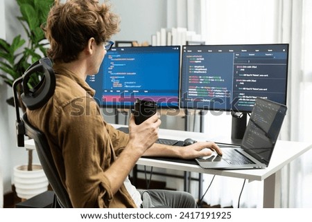 Working IT developer holding coffee cup with looking online software on pc at modern office on coding application screens, creating updated latest program firmware information version concept. Gusher.