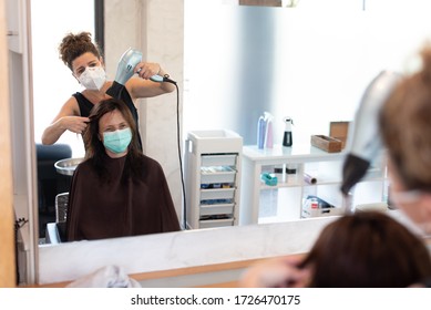 Working during covid-19 or coronavirus concept. A professional hairdresser cutting the hair to a client, reflected in the mirror with copy space. - Powered by Shutterstock