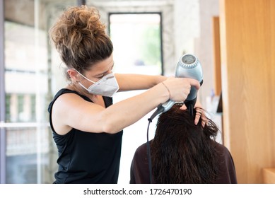 Working during covid-19 or coronavirus concept. Hairstylist drying the hair of a client in a beauty center. - Powered by Shutterstock