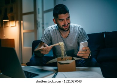 Working And Eating Late. Man Eating Chinese Food And Using Mobile Phone. Night Scene