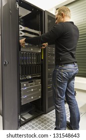 A working IT engineer / technician installing a server in a rack at the data center.