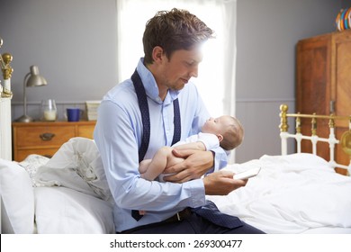 Working Father Holding Baby And Checking Mobile Phone