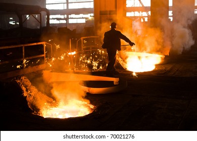 Working in a foundry. Workers looking down, red color is a reflection of the molten metal. - Powered by Shutterstock