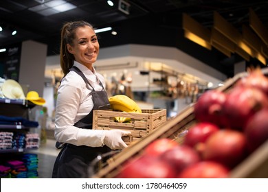 Working in grocery store. Supermarket worker supplying fruit department with food. Female worker holding crate with fruits. - Powered by Shutterstock