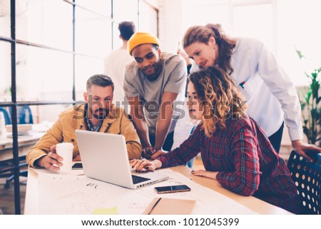 Working group discussing ideas for project sharing opinions while checking business plan on laptop, killed female web designer presenting to colleagues her job using netbook in coworking space