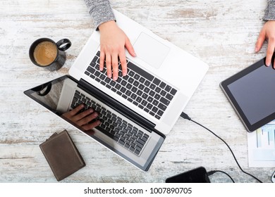 A working womanâ??s hand at a table with laptop,tablet and phone.