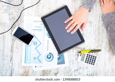 A working woman’s hand at a table with laptop,tablet and phone.
