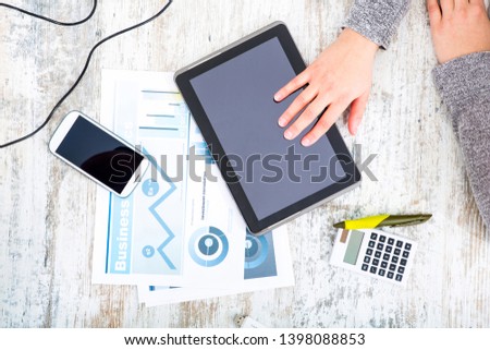 A working woman’s hand at a table with laptop,tablet and phone.