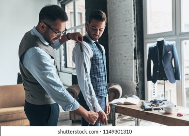 Working hard to achieve best results. Young fashionable designer measuring client?s sleeve while standing in his workshop  - Powered by Shutterstock