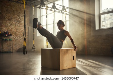 Working hard. Side view of athletic woman in sportswear training legs at gym.