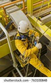 Working At Height. A Commercial Abseiler With Respiratory Protection And Fall Arrestor Device Managing His Rope Access For Working At Height.