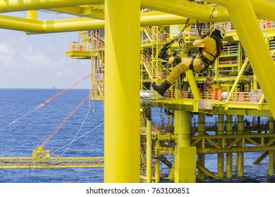 Working At Height. A Commercial Abseiler With Respiratory Protection And Fall Arrestor Device Managing His Rope Access For Working At Height.