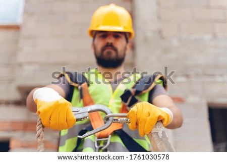 Working at height equipment. Fall arrestor device for worker with double hooks for safety body harness on selective focus. Construction as a background.