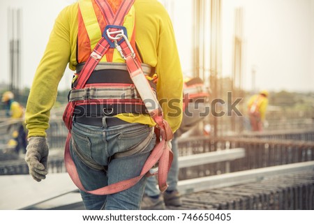 Working at height equipment. Fall arrestor device for worker with hooks for safety body harness on selective focus. Worker as a background.