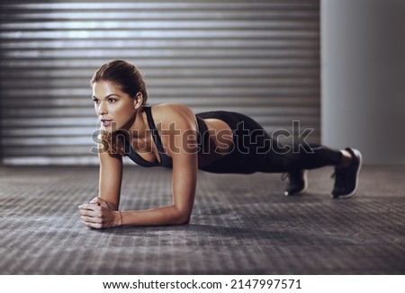 Working her core muscles to the max with some planks. Shot of a young woman doing a plank exercise at the gym.