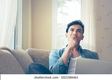 Working At Home Concept. Young Asian Man Laying on Sofa With Happy Face Looking Out Window Forefinger  Up, I Got New Ideas. Business and Social distance lockdown curfew and work from home concept. - Powered by Shutterstock