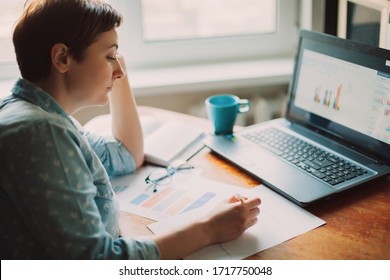 Working at home. Woman accountant analytics doing chart analysis in business, sitting at the table with laptop - Powered by Shutterstock