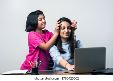 Working Indian mom works from home office with kid in pandemic. Woman and cute child using laptop. Kid giving head massage to mother for stress relief