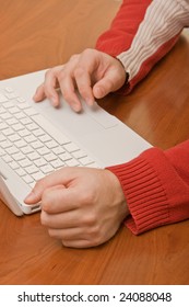 Working with a laptop in red pullover on a wooden table