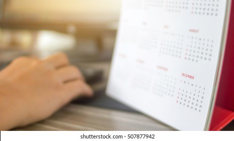 working in the last month of year ,calendar with hand on keyboard and monitor blur background , december 
