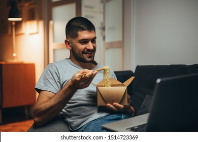 Working Late From His Home. Man Eating Chinese Food And Using Laptop Computer