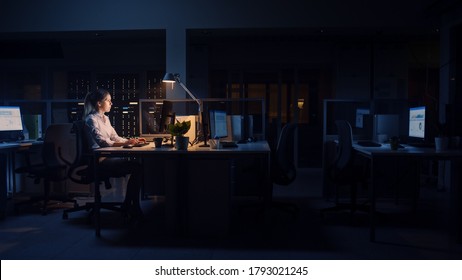 Working Late At Night In The Office: Businesswoman Uses Desktop Computer, Analyzing, Using Documents, Solving Problems, Finishing Important Project. Diligent Ambitious Young Worker. Side View