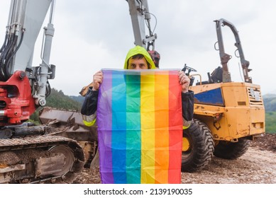 Working Man On A Construction Site Holding A Rainbow Lgbt Pride Flag Demanding Equal Treatment At His Job. Concept Of Sexual Discrimination In Employment.